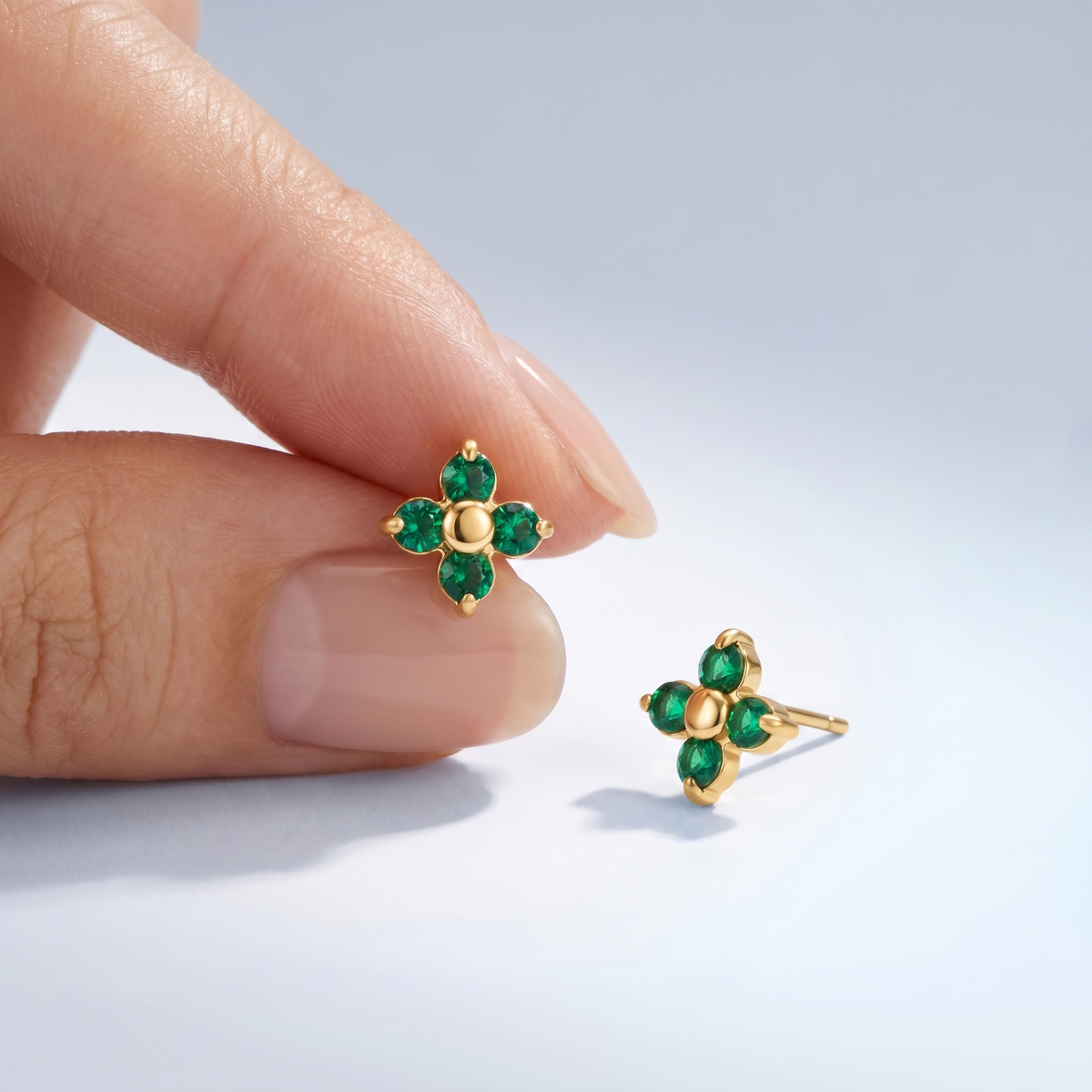Pendientes flor verde esmeralda bañados en oro de 18K sostenidos entre los dedos, para ver el tamaño real