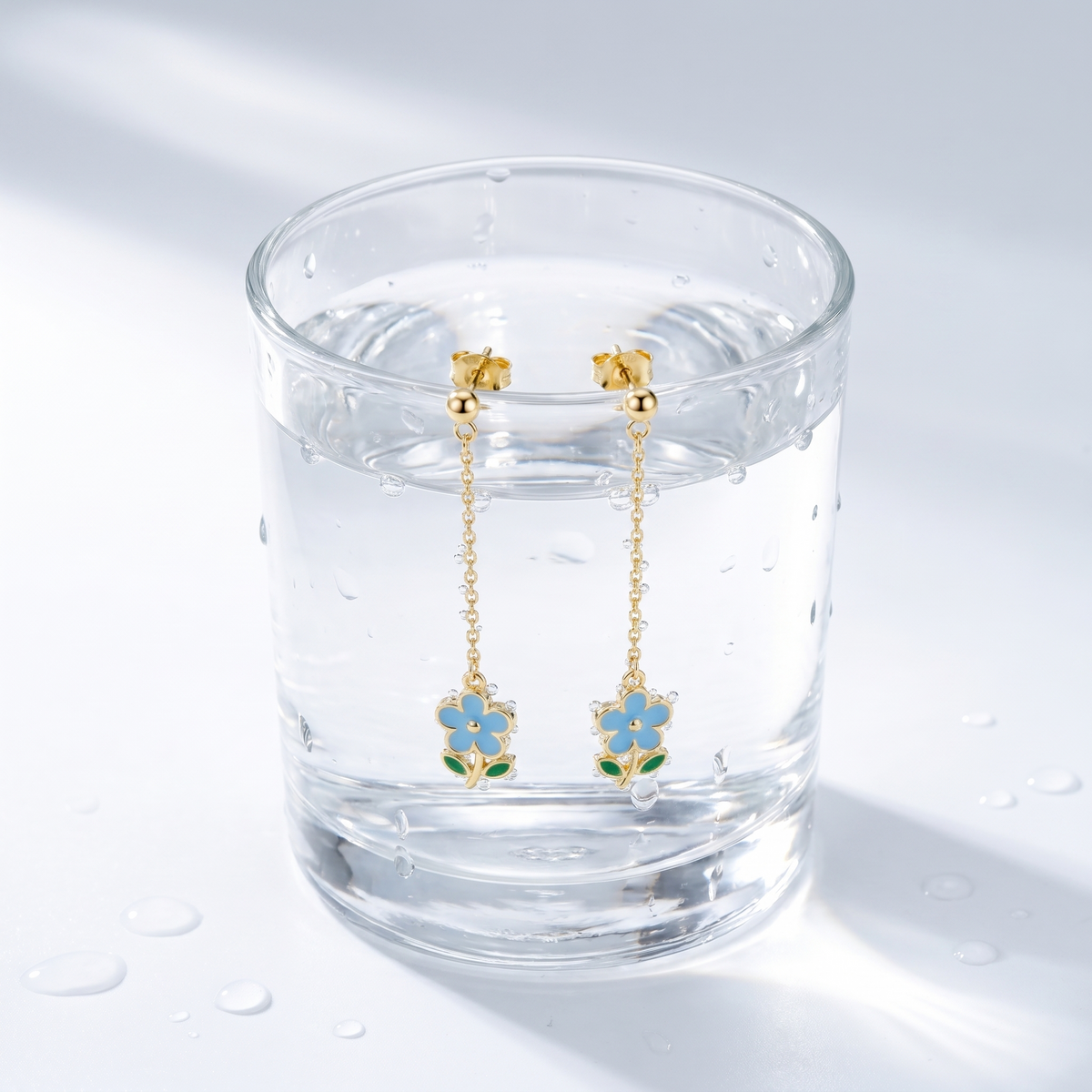 Pendientes gota con flor bañados en oro de 18K en un vaso de agua