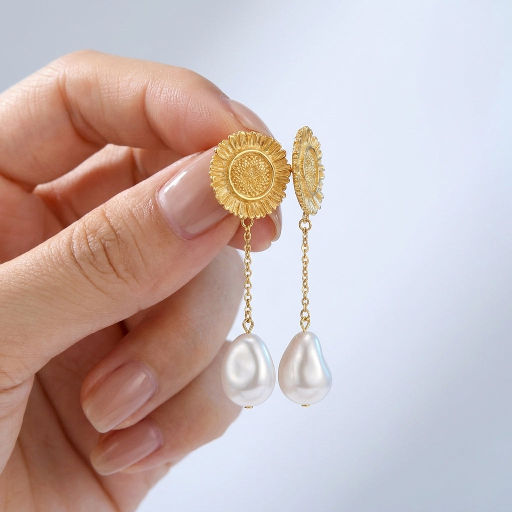Pendientes colgantes de sol y perla bañados en oro de 18K sostenidos entre los dedos, para ver el tamaño real